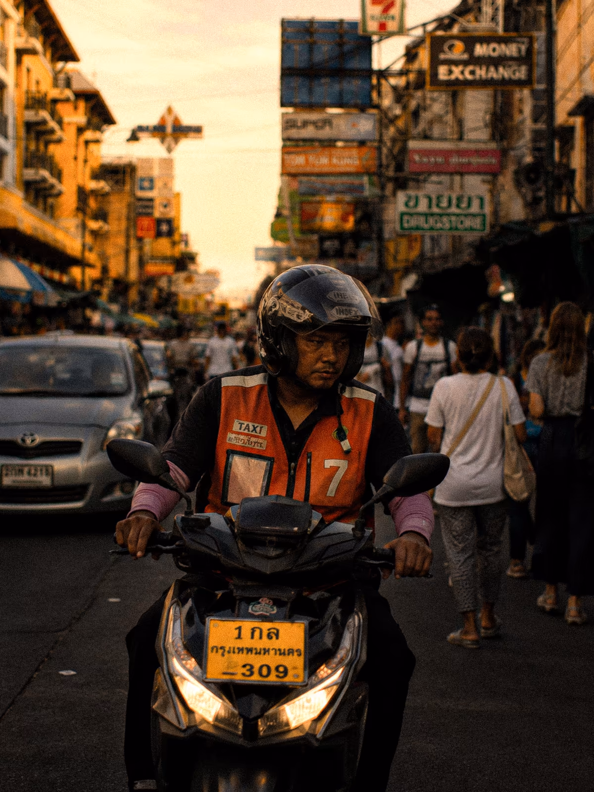 Motorbike rider moving through warm Bangkok traffic