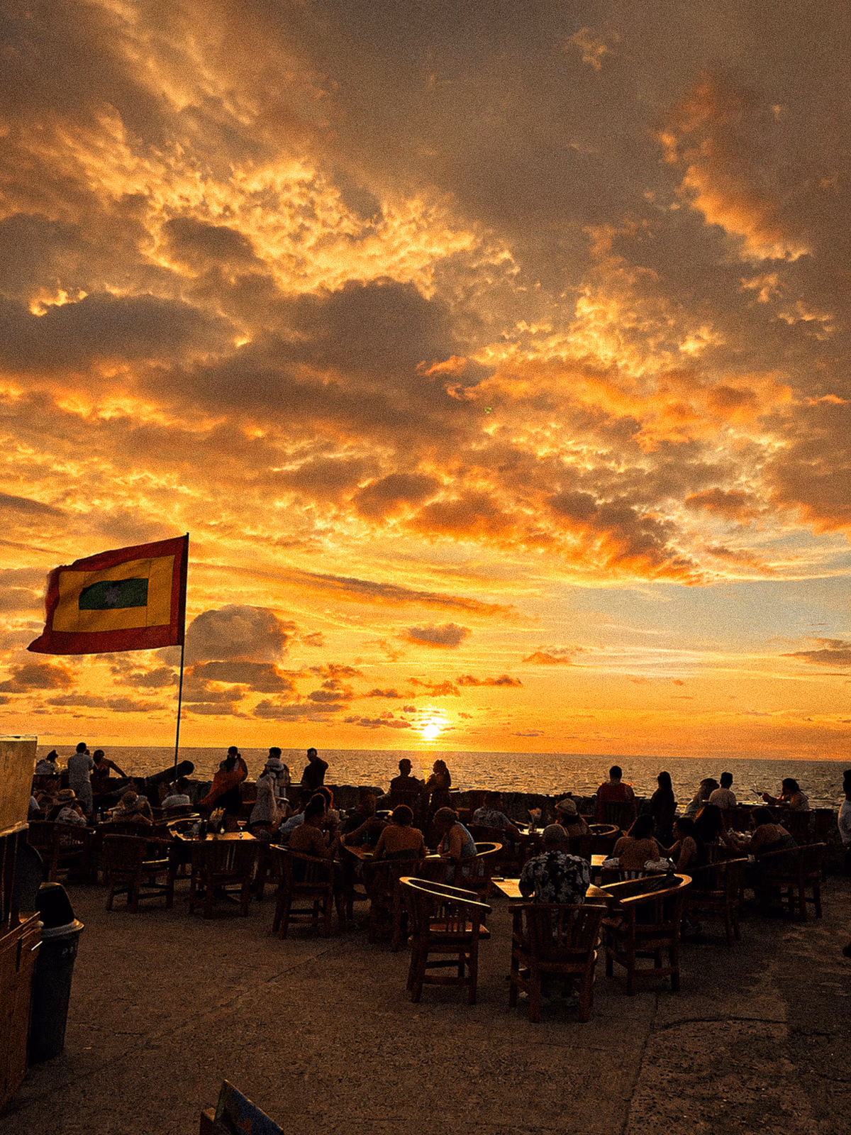 A Caribbean sunset above the sea with distant people reduced to unrecognisable silhouettes