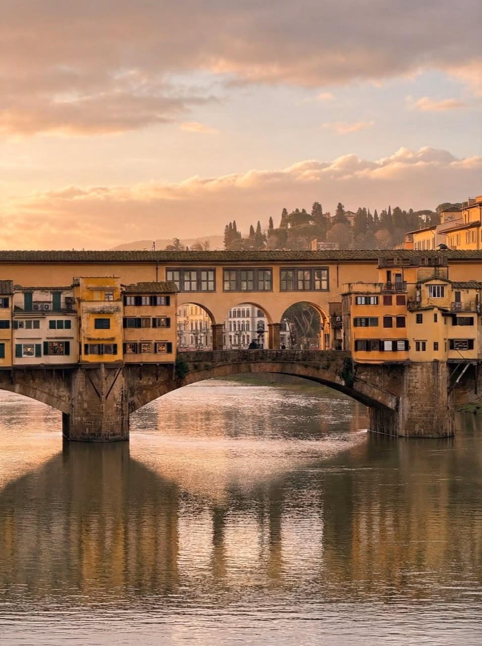 Ponte Vecchio reflected in the Arno under soft golden light