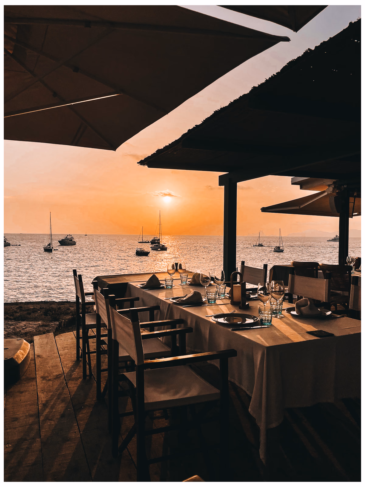 An empty restaurant table facing the sea at sunset in Formentera