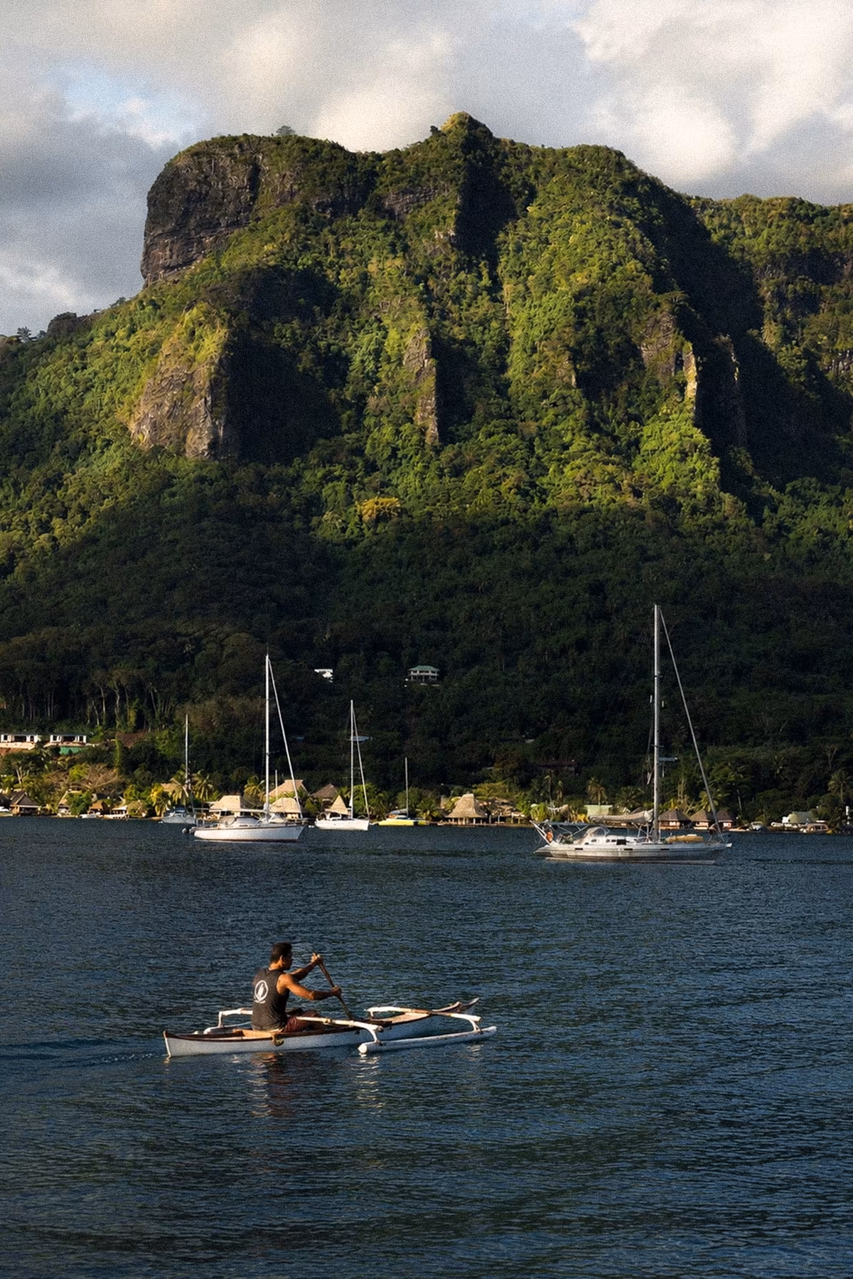 An outrigger canoe crossing a Moorea bay beneath volcanic peaks