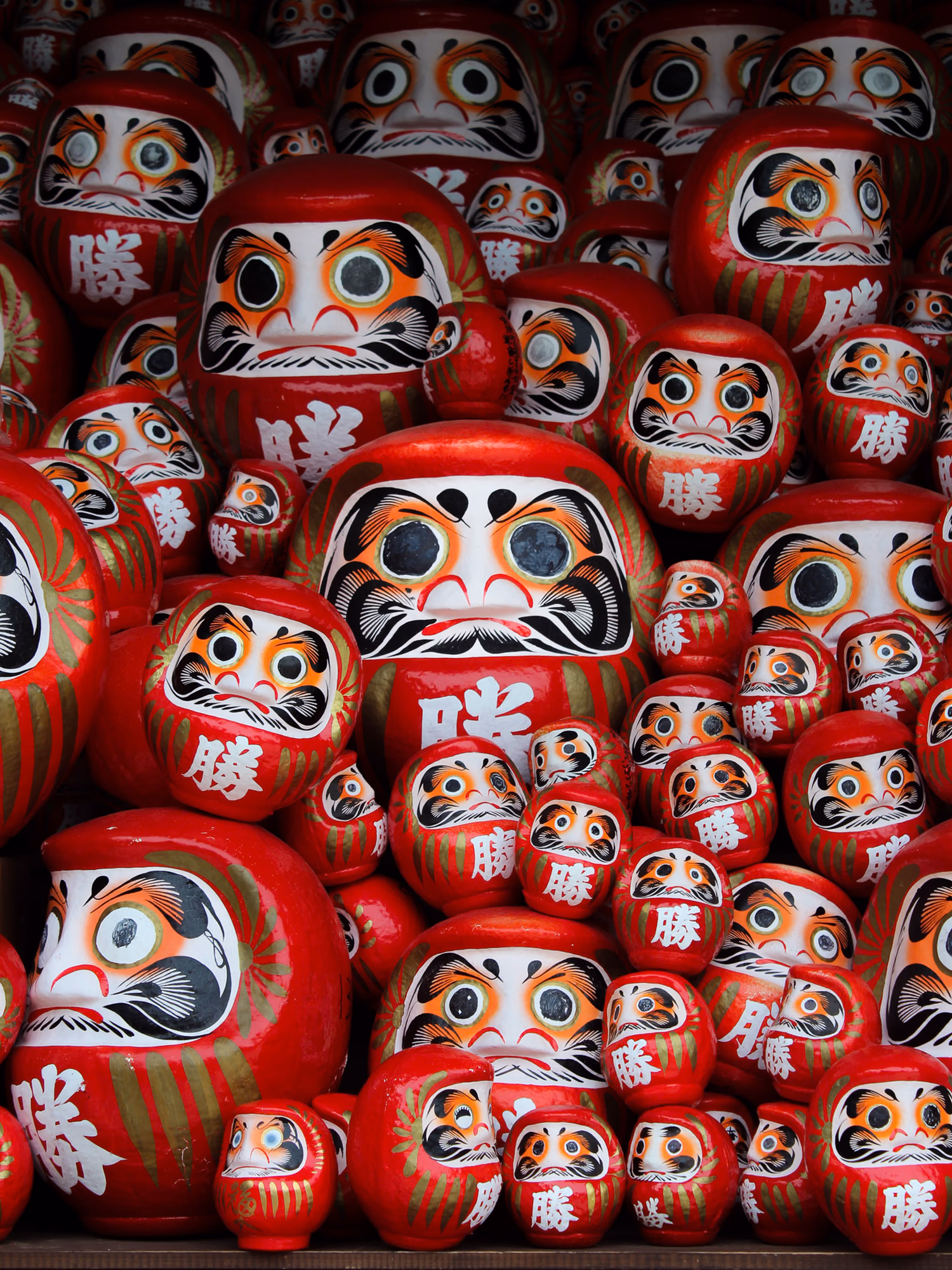 A tightly composed wall of traditional red daruma dolls in Japan