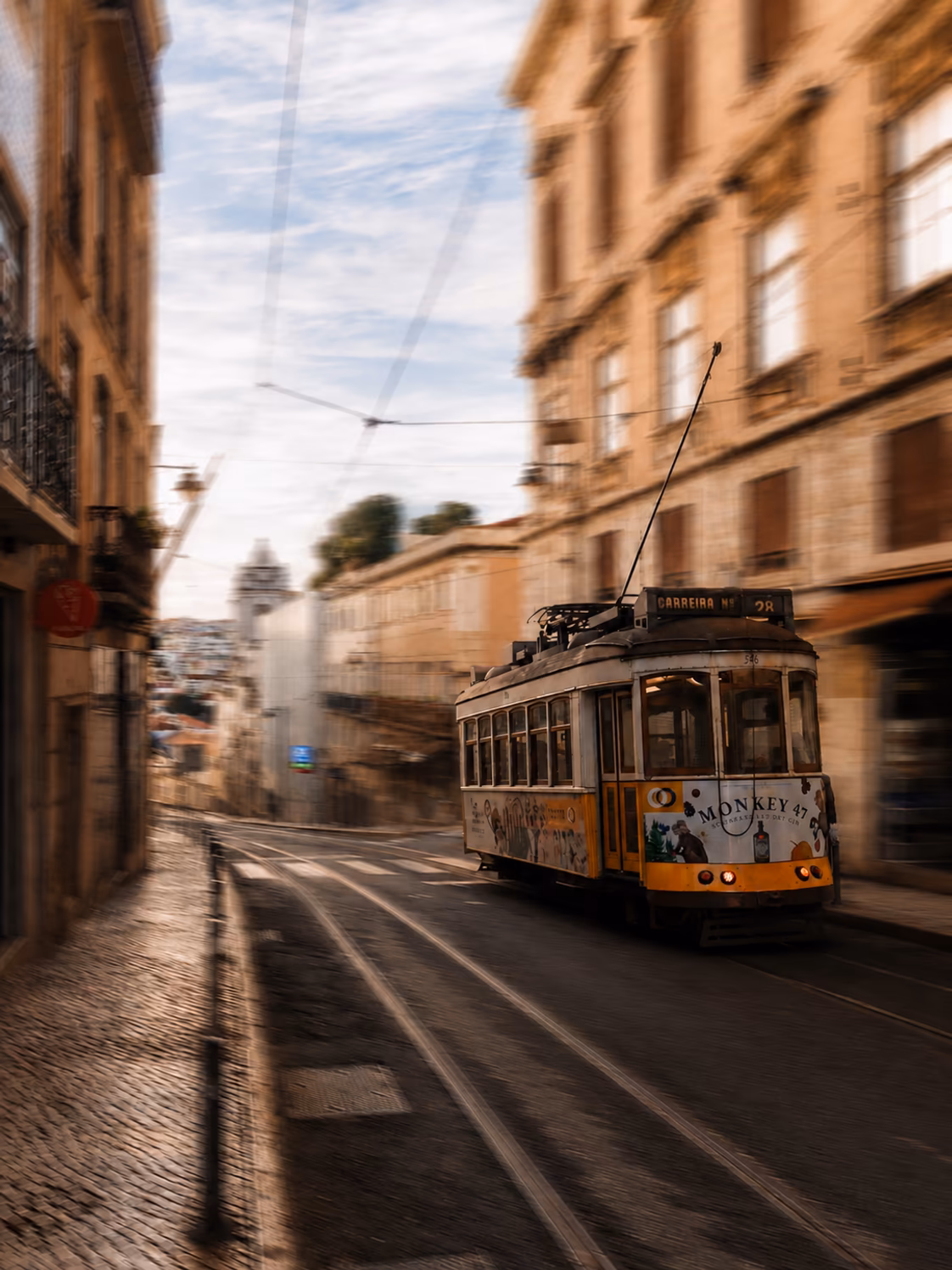 A Lisbon tram moving through a narrow street with intentional motion blur and no people visible
