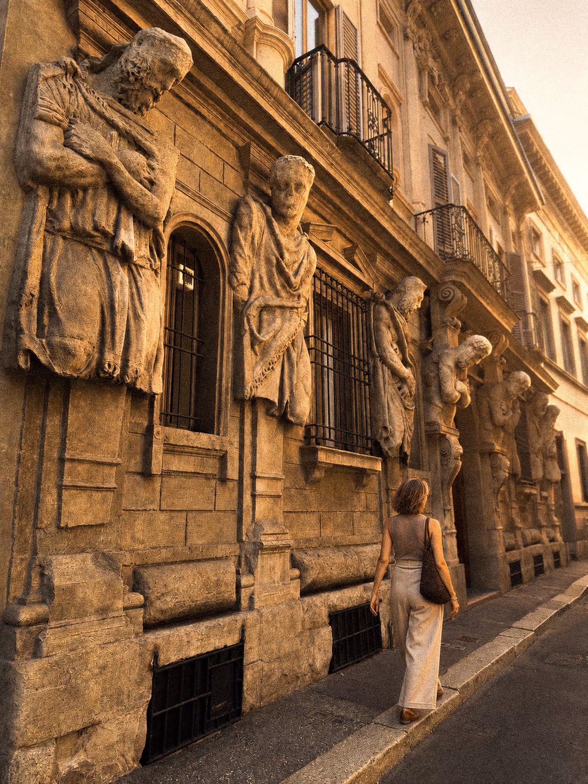 A figure walking beneath historic stone caryatids in Milan