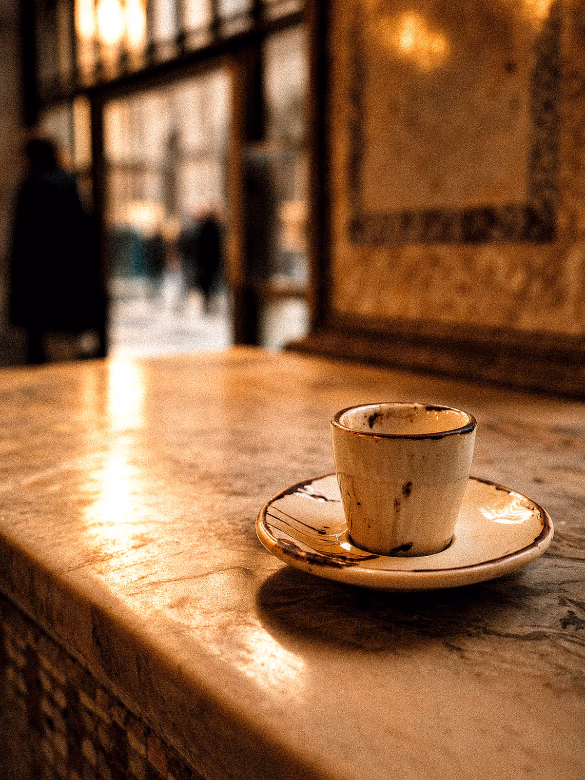 An espresso cup catching warm light on a Milan café counter
