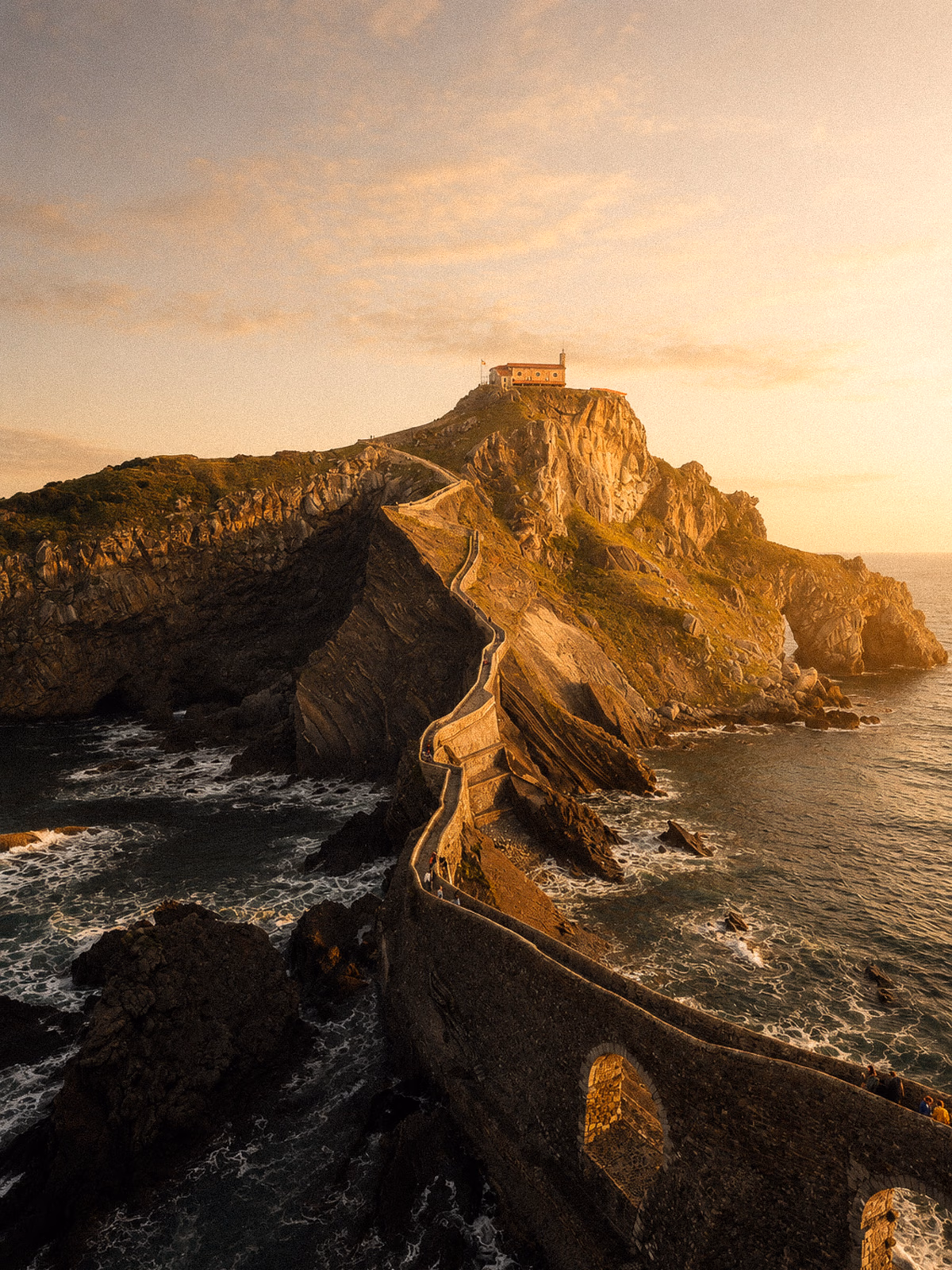 The rocky Atlantic coast at Gaztelugatxe beneath warm evening light with no people visible