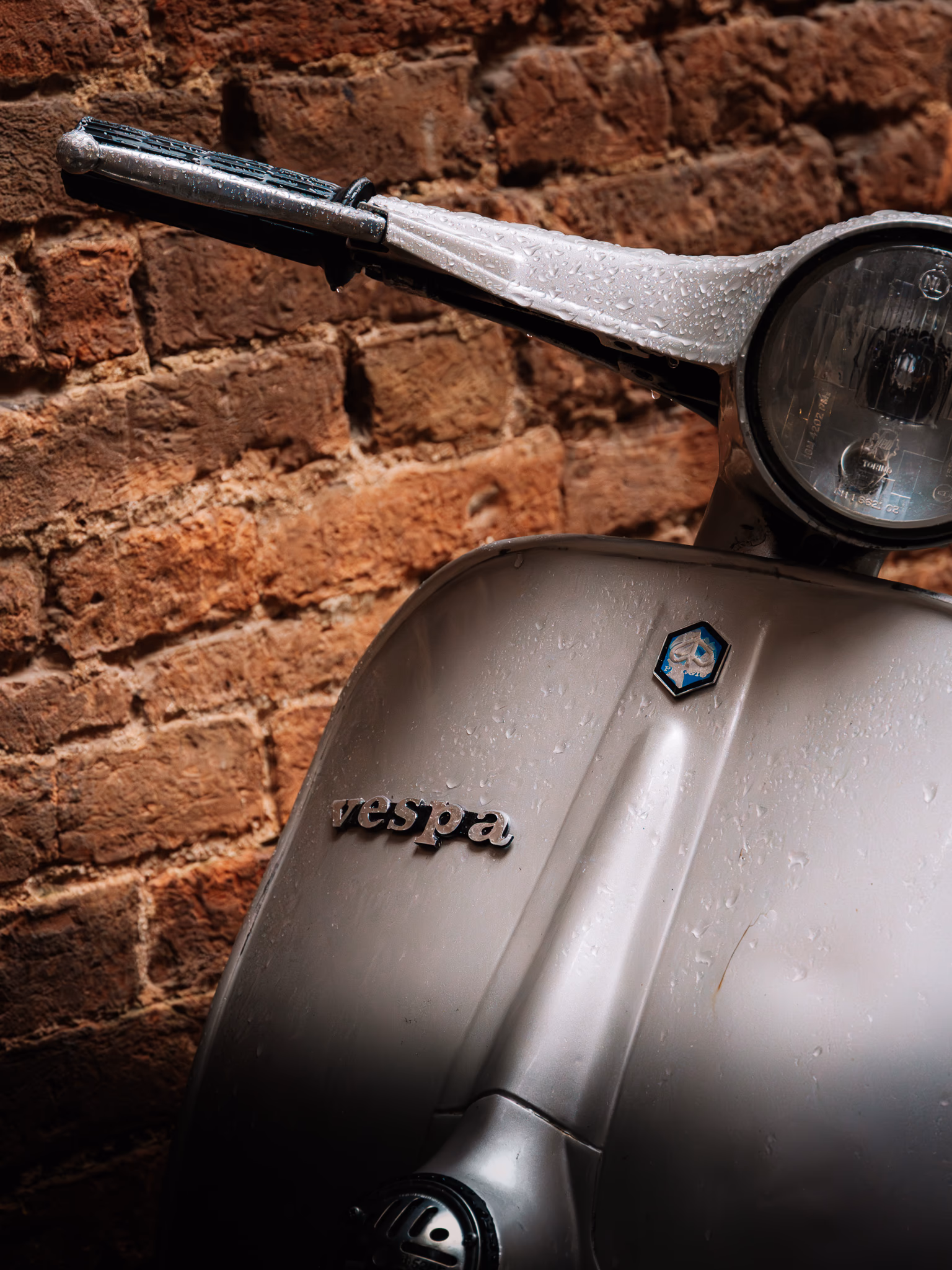 A Vespa detail against a warm brick wall
